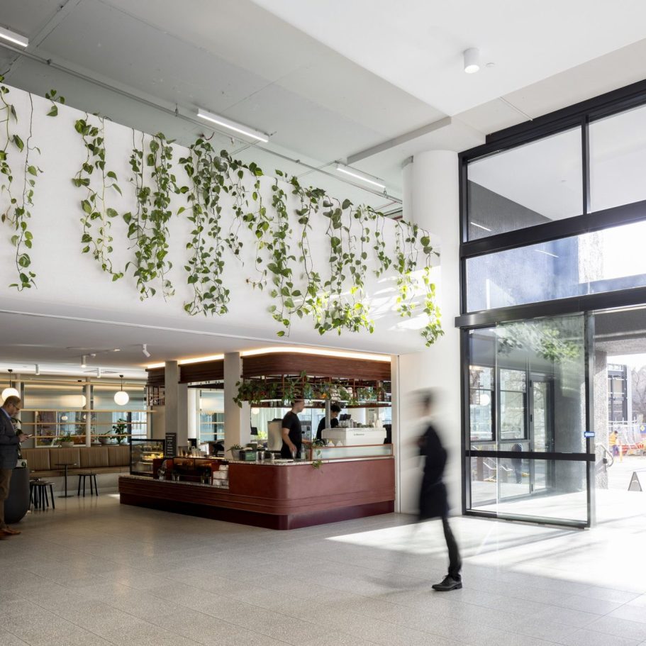 Modern lobby with hanging plants, seating area, and large glass entrance.