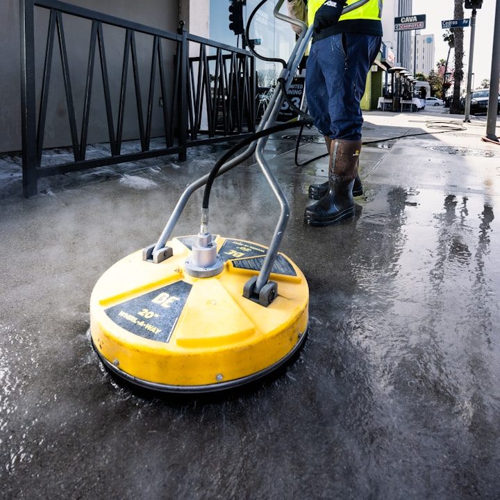 Circular yellow floor scrubber cleaning a wet surface.